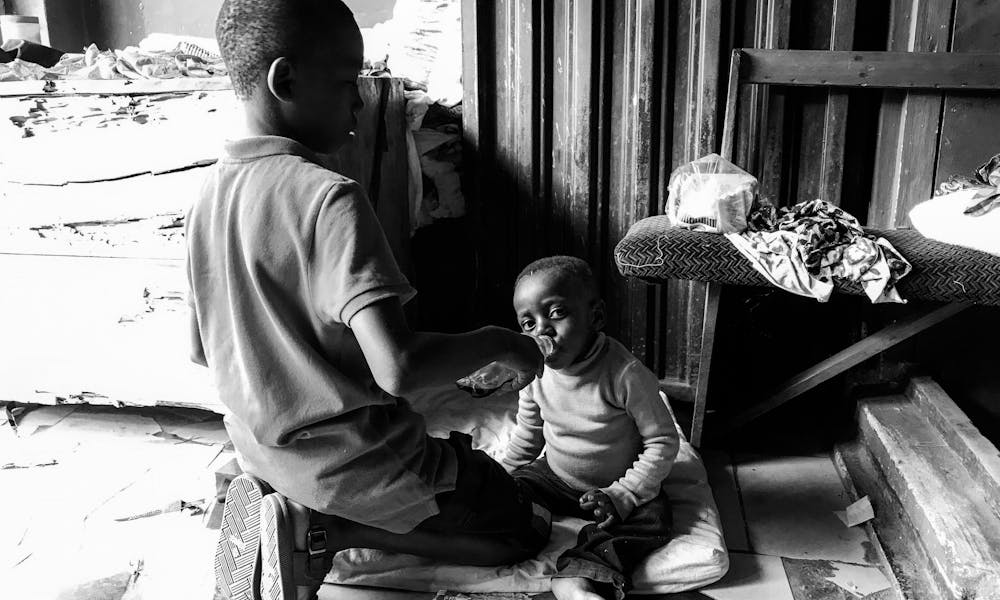 A touching scene of a child feeding another child in black and white. .pexels