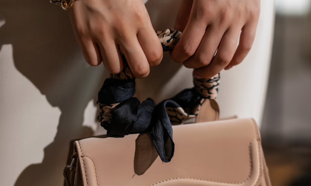 Close-up of hands holding a fashionable beige handbag with bracelets, stylish and elegant. .pexels