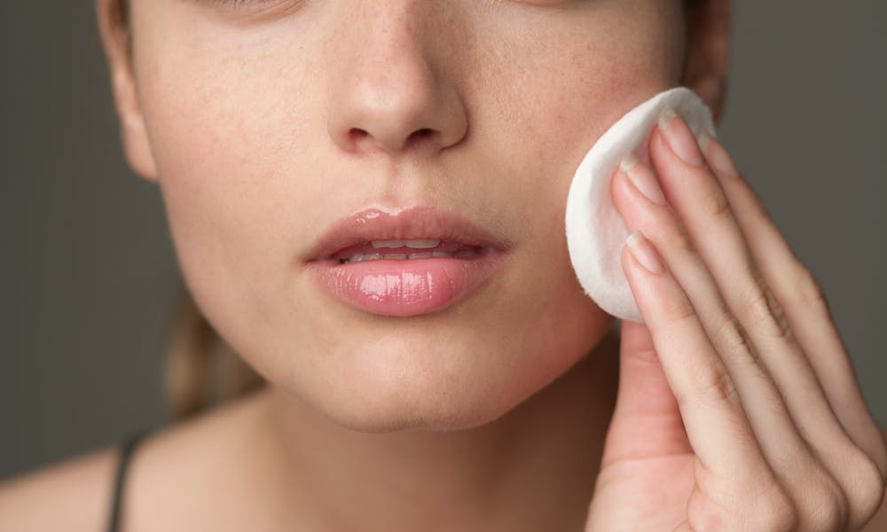 Young woman using a cotton pad for skincare, highlighting beauty routine. .pexels