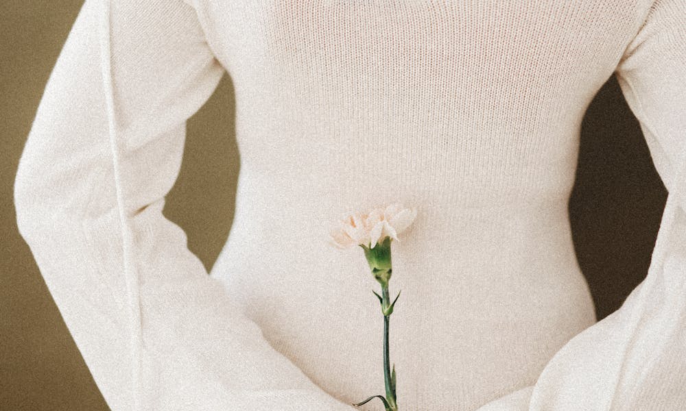 Rear view of a woman in a white dress holding a single carnation flower. .pexels